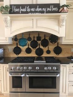 an oven with pots and pans hanging on the wall above it's burners