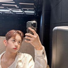 a young man taking a selfie in front of a mirror with his cell phone