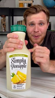 a man holding a bottle of simply pineapple juice