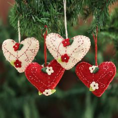 three red and white hearts hanging from a christmas tree