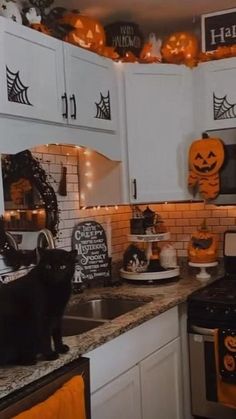 a kitchen decorated for halloween with black cats and pumpkins