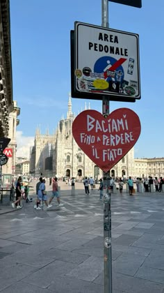 a street sign in the middle of a city with people walking around it and buildings in the background