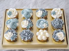 cupcakes decorated with blue and white frosting on a tray