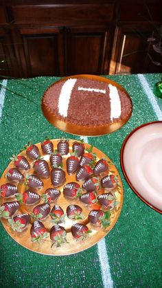 two plates with strawberries and chocolate covered footballs on them sitting on a table