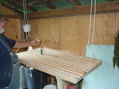 a man standing in front of a wooden table with ropes hanging from it's sides