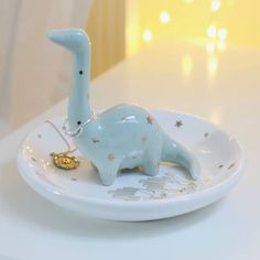 a small blue dinosaur figurine on a white plate with gold stars around it