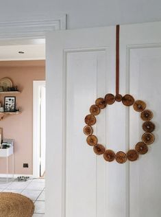 a door with a wreath hanging on it's side in front of a pink wall