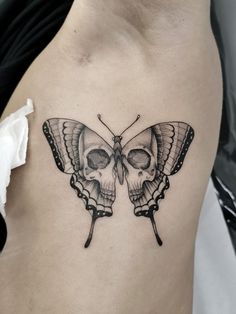 a woman's stomach with a skull and butterfly tattoo on the back of her body