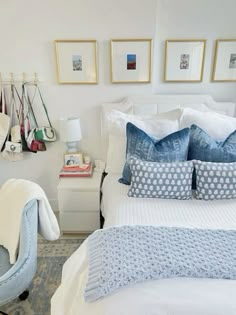 a bed with blue and white pillows in a bedroom next to pictures on the wall