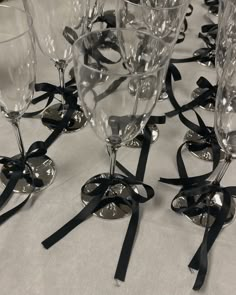 there are many wine glasses with black ribbons on the tablecloth and one is empty