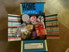 an open box filled with assorted items on top of a carpeted floor next to a sign that says home is