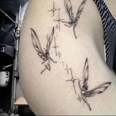 three small tattoos on the side of a woman's thigh, one with two hummings