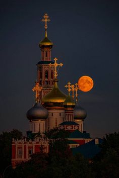 the full moon is seen over an old church