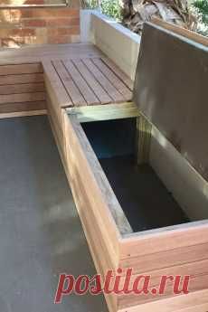 a wooden bench sitting on top of a cement floor next to a tree and bushes