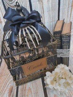 a birdcage filled with books sitting on top of a wooden table next to a white flower