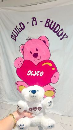 a person holding a teddy bear in front of a banner