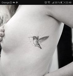 a woman's stomach with a hummingbird tattoo on her left side ribcage