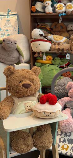 a teddy bear sitting on top of a chair next to a table filled with stuffed animals