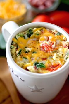 a close up of a cup of food with broccoli and tomatoes in the background