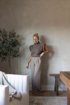 a woman standing next to a white couch in a living room with a potted plant