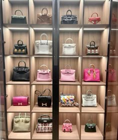 a display case filled with lots of different types of purses and handbags on wooden shelves