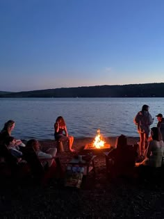 people sitting around a campfire on the beach