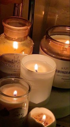 three candles sitting next to each other on top of a table in front of jars