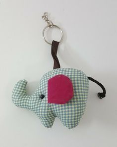 an elephant keychain with a pink patch on it's back is hanging from a hook