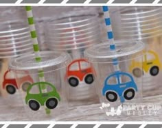 four plastic cups with different colored cars on them and one has a straw in the middle