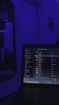 a laptop computer sitting on top of a desk in front of a blue lit mirror