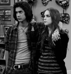 the young man and woman are standing next to each other in front of bookshelves