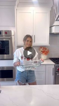 a woman standing in a kitchen holding a tray