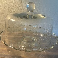 a glass cake dish with a lid on a wooden table