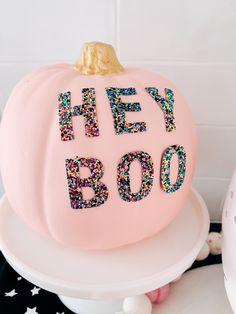 a pink cake with the words hey booo on it and sprinkles