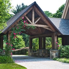 a wooden gazebo surrounded by lush green trees and shrubs with pink flowers on it