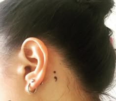 a woman's left ear with small black dots on the back of her right ear