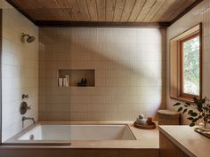 a bath tub sitting under a window next to a sink