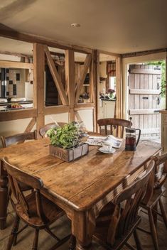 a wooden table sitting in the middle of a kitchen next to an open door and window