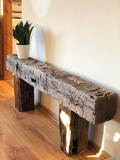 a wooden bench sitting on top of a hard wood floor next to a plant pot