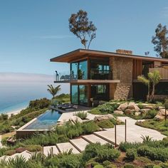 a modern house overlooking the ocean on top of a hill