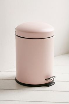 a pink trash can sitting on top of a white table