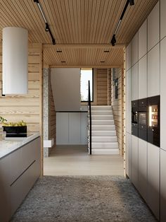 an open kitchen with stairs leading up to the upper floor and white counter tops on either side