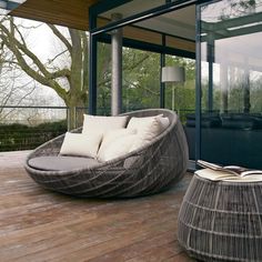 an outdoor living area with large windows and furniture on the wooden flooring, along with glass doors leading outside