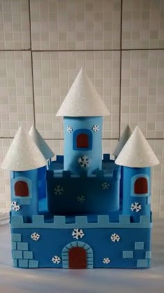 a blue and white castle with snowflakes on it's roof sits in front of a tiled wall