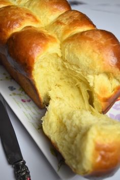 a long loaf of bread sitting on top of a white plate next to a knife