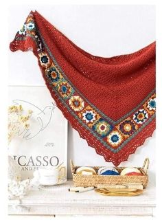 a crocheted shawl is hanging on a shelf