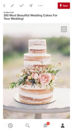 a three tiered cake with flowers and greenery sits on top of a table