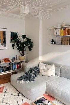 a living room filled with lots of furniture and bookshelves next to a white wall