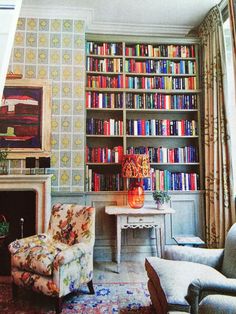 a living room filled with lots of furniture and bookshelves covered in colorful books