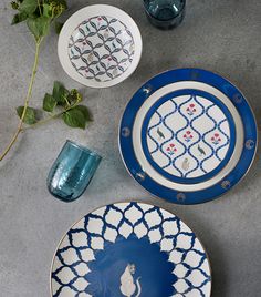 three plates with designs on them sitting next to a plant and glass vase in the background